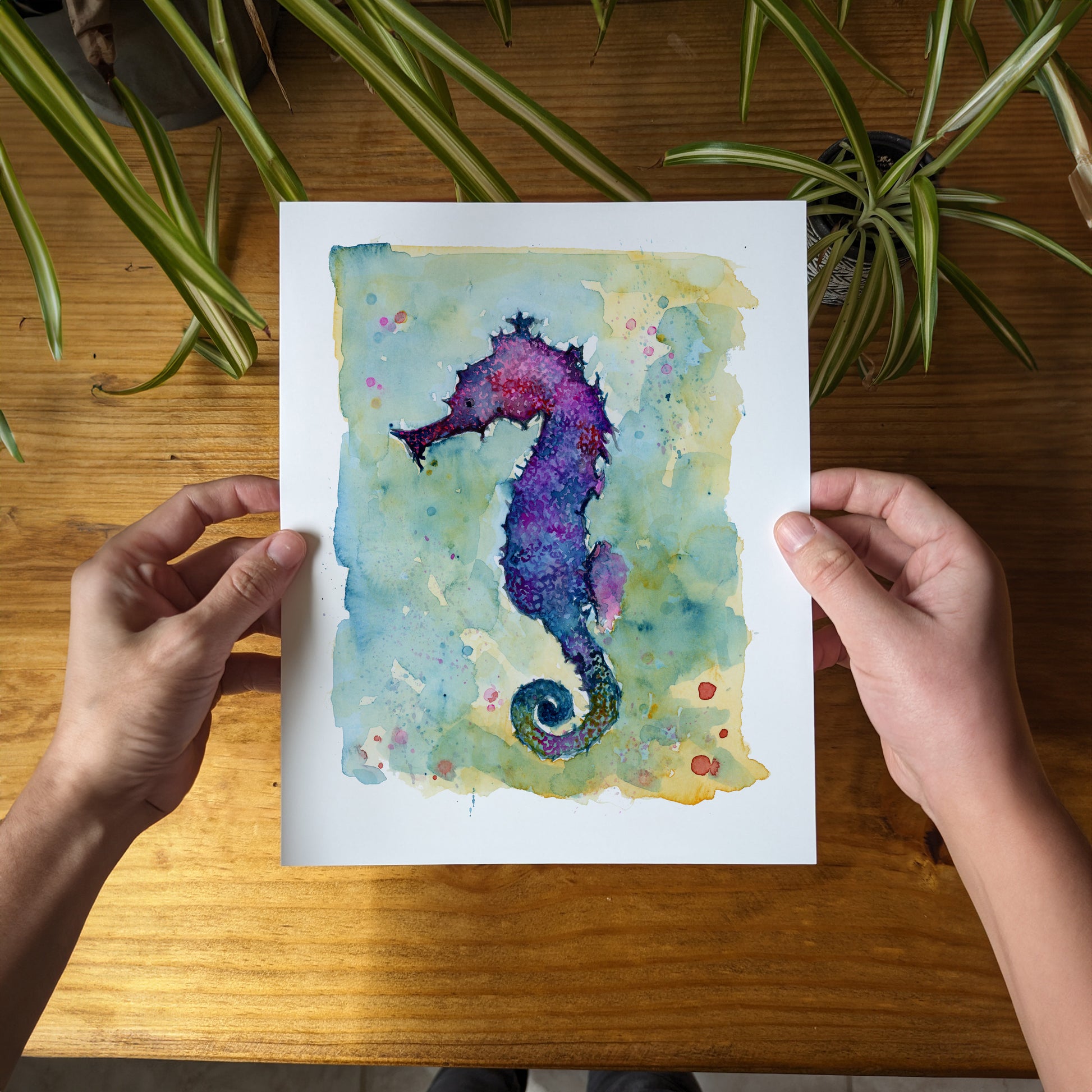 a person holding a card with a watercolor painting of a sea horse