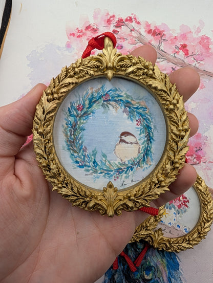 Chickadee in a Winter Wreath watercolor ornament in a gold wreath frame, held in hand